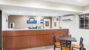 A Days Inn reception desk with a clock, a coffee machine, and a 'No Soliciting' sign. - Days Inn by Wyndham El Centro (El Centro)