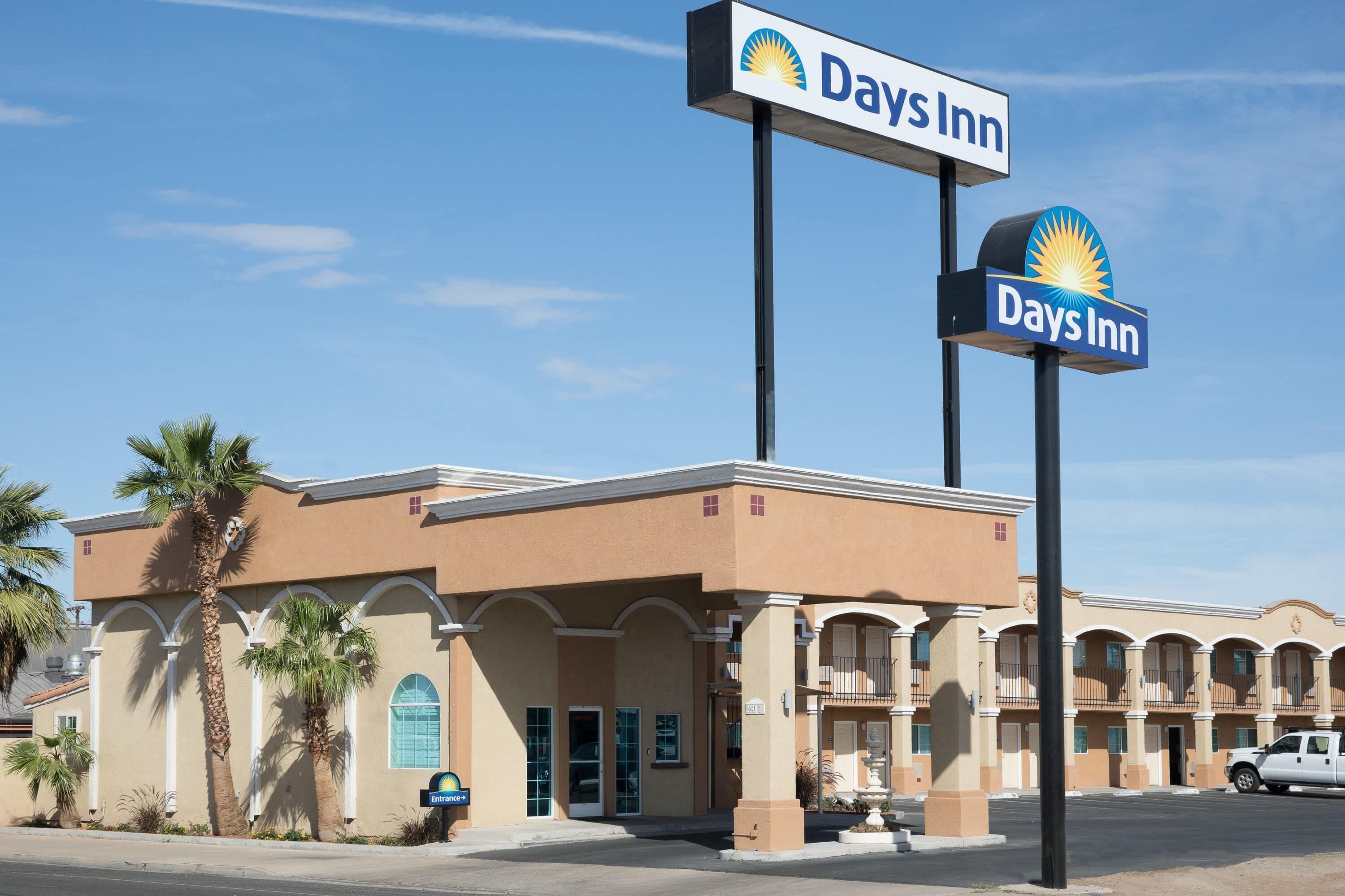 A Days Inn hotel with a clear sign, a parking lot, and a building facade with a symmetrical design.