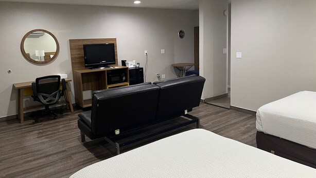 A hotel room with a bed, a desk with a chair, a television, a microwave, and a small table with a lamp. - Days Inn by Wyndham El Centro (El Centro)