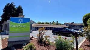 A SureStay hotel sign with a clear view of the building and parked cars in the background. - SureStay Hotel by Best Western Santa Cruz (Santa Cruz)