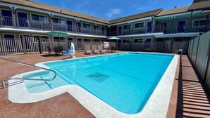 A swimming pool with a diving board, lounge chairs, and umbrellas. - SureStay Hotel by Best Western Santa Cruz (Santa Cruz)