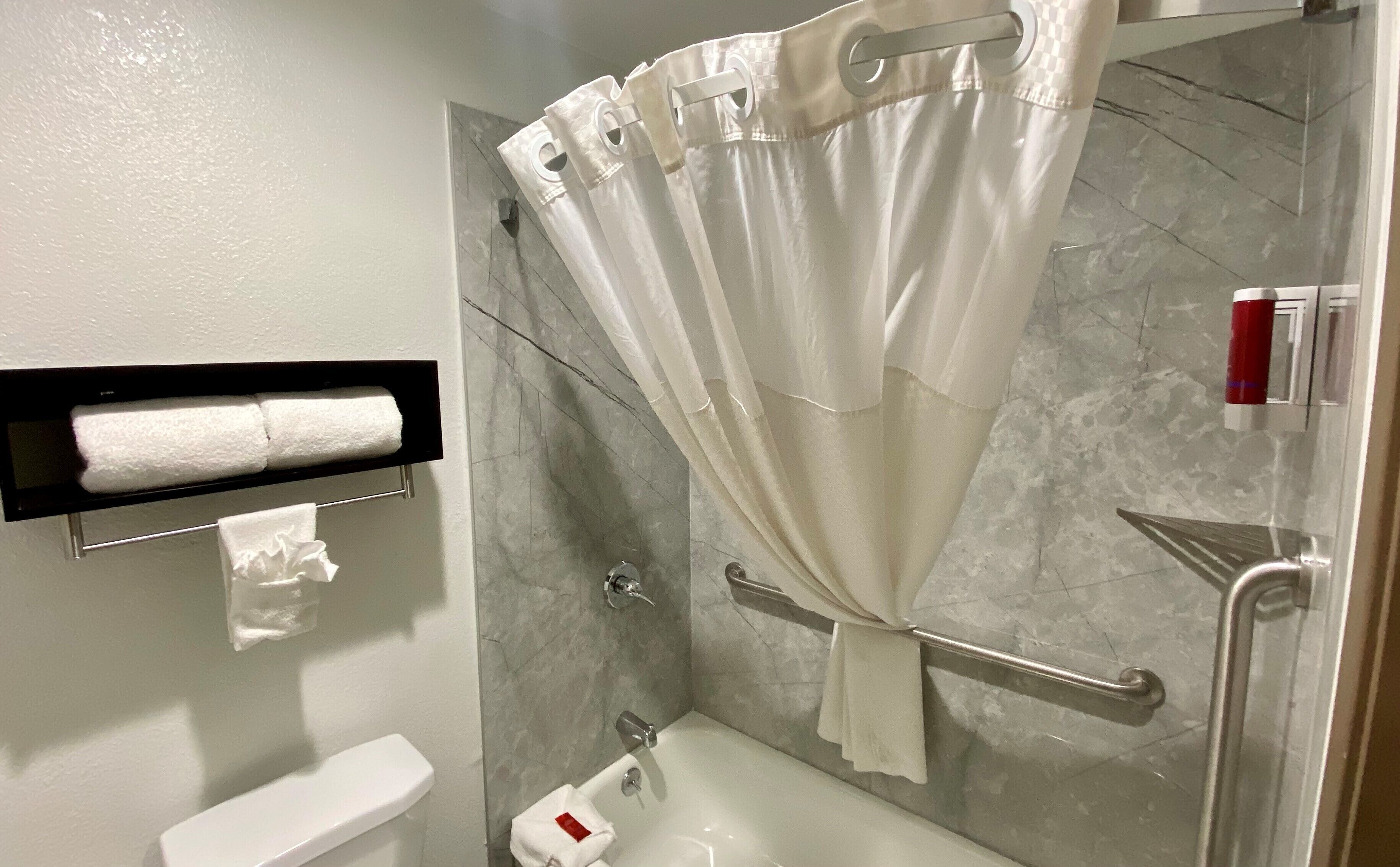 A bathroom with a shower, toilet, and a towel rack.