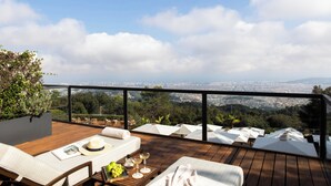 A rooftop terrace with wooden flooring, white lounge chairs, and a table set for dining. - METT Barcelona GL – A Leading Hotel of the World (Barcelona)