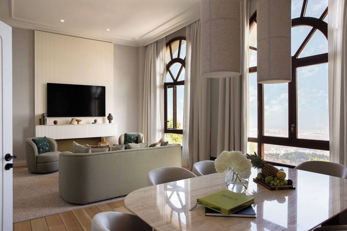Uma sala de estar moderna com uma televisão de tela plana, um sofá e uma área de refeições com mesa e cadeiras.