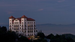 A multi-story building with a red-tiled roof, multiple balconies, and a view of the surrounding landscape. - METT Barcelona GL – A Leading Hotel of the World (Barcelona)