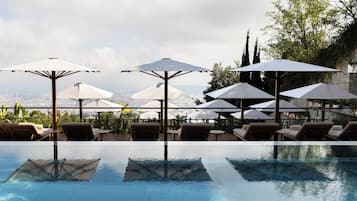 Una piscina techada, una piscina al aire libre, sombrillas