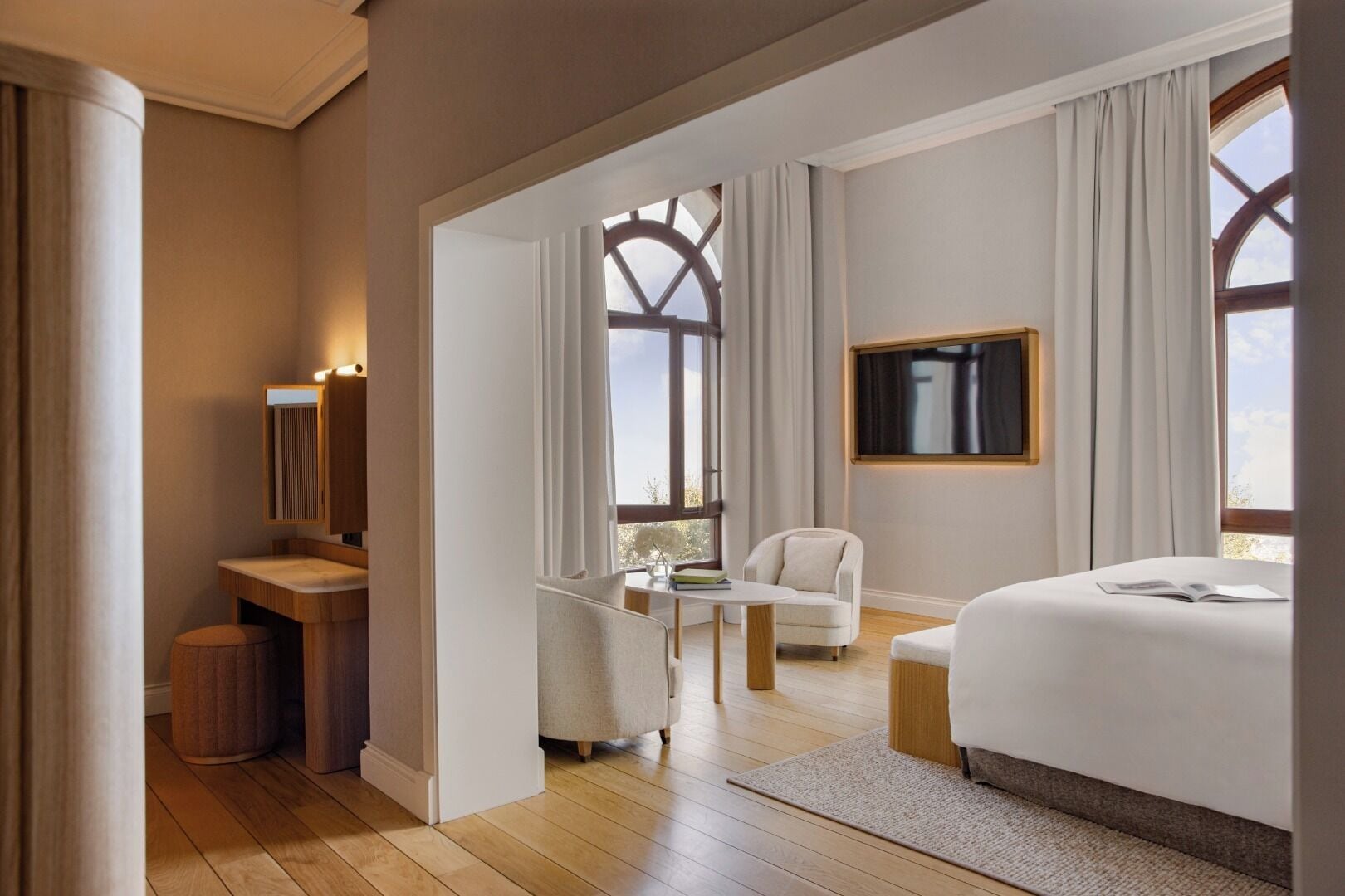 Una habitació d'hotel moderna amb un llit gran, una taula de treball amb una cadira, una taula petita i un televisor.