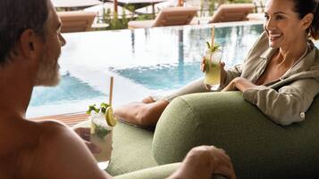 A couple relaxing by a poolside lounge with a drink in hand.