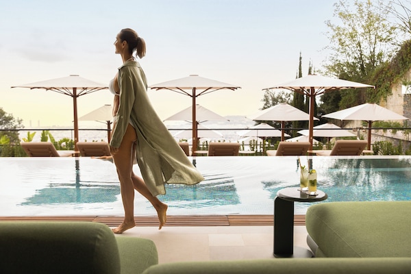 Una piscina techada, una piscina al aire libre, sombrillas