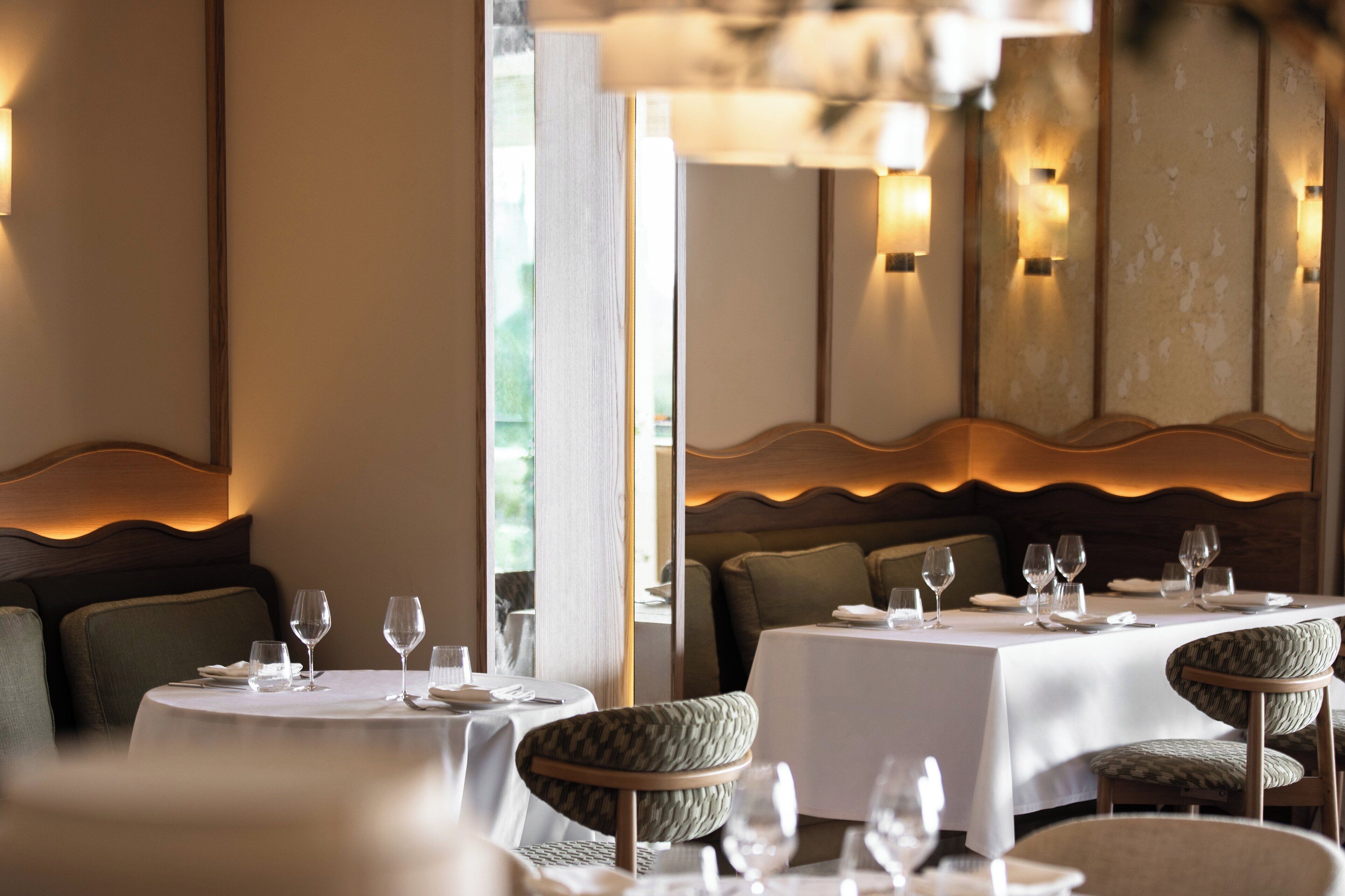 Um restaurante com mesas redondas, cadeiras acolchoadas e um ambiente acolhedor.