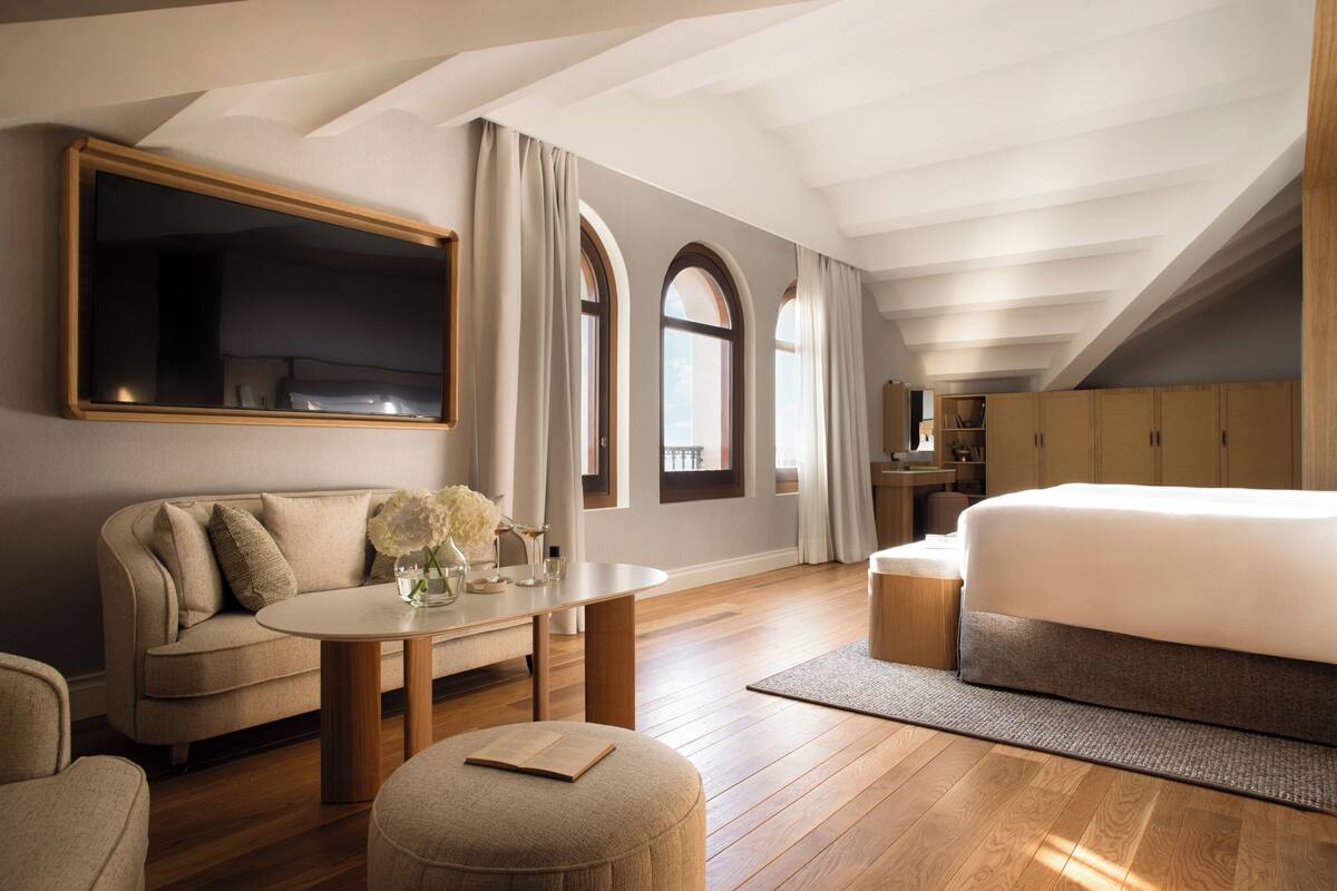 Quarto moderno com uma cama grande, sofá, mesa de jantar e televisão.