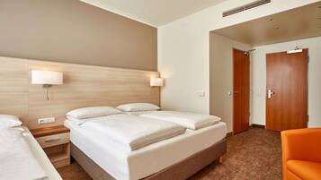 Ein Hotelzimmer mit einem großen Bett, Nachttischen, einem Beistelltisch, einem orangefarbenen Sessel und einem Holz-Kopfteil.