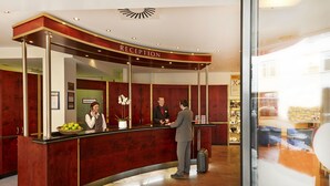 A reception desk with a curved design, a reception area, and a visible counter. - H+ Hotel Berlin Mitte (Berlin)