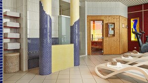 A modern spa area with a sauna, exercise equipment, and neatly arranged towels. - H+ Hotel Berlin Mitte (Berlin)