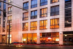 Un hotel de varios pisos con fachada moderna, grandes ventanales y un restaurante visible en la planta baja.