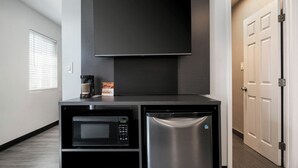 A compact kitchenette with a microwave, a small refrigerator, and a flat-screen TV mounted on the wall. - Studio 6 Rosemead, CA – Pasadena (Rosemead)