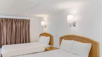 Habitación de hotel con dos camas, cabecero de madera, mesita de noche y dos lámparas de pared.