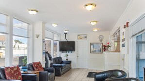 A spacious living area with a large TV, comfortable seating, and a view of the outside. - Americas Best Value Inn & Suites Hyannis Cape Cod (Hyannis)