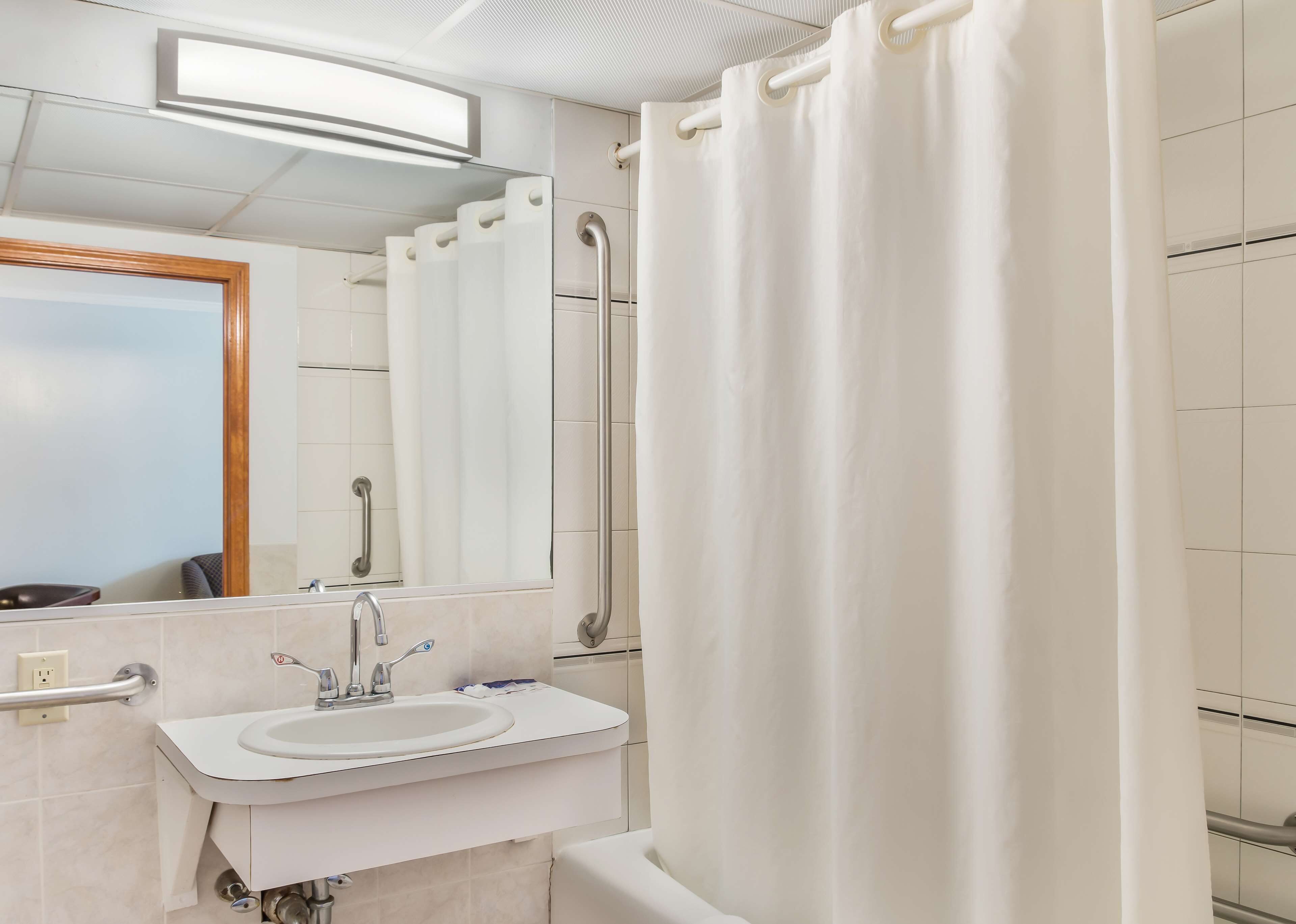 A bathroom with a sink, mirror, and shower curtain.