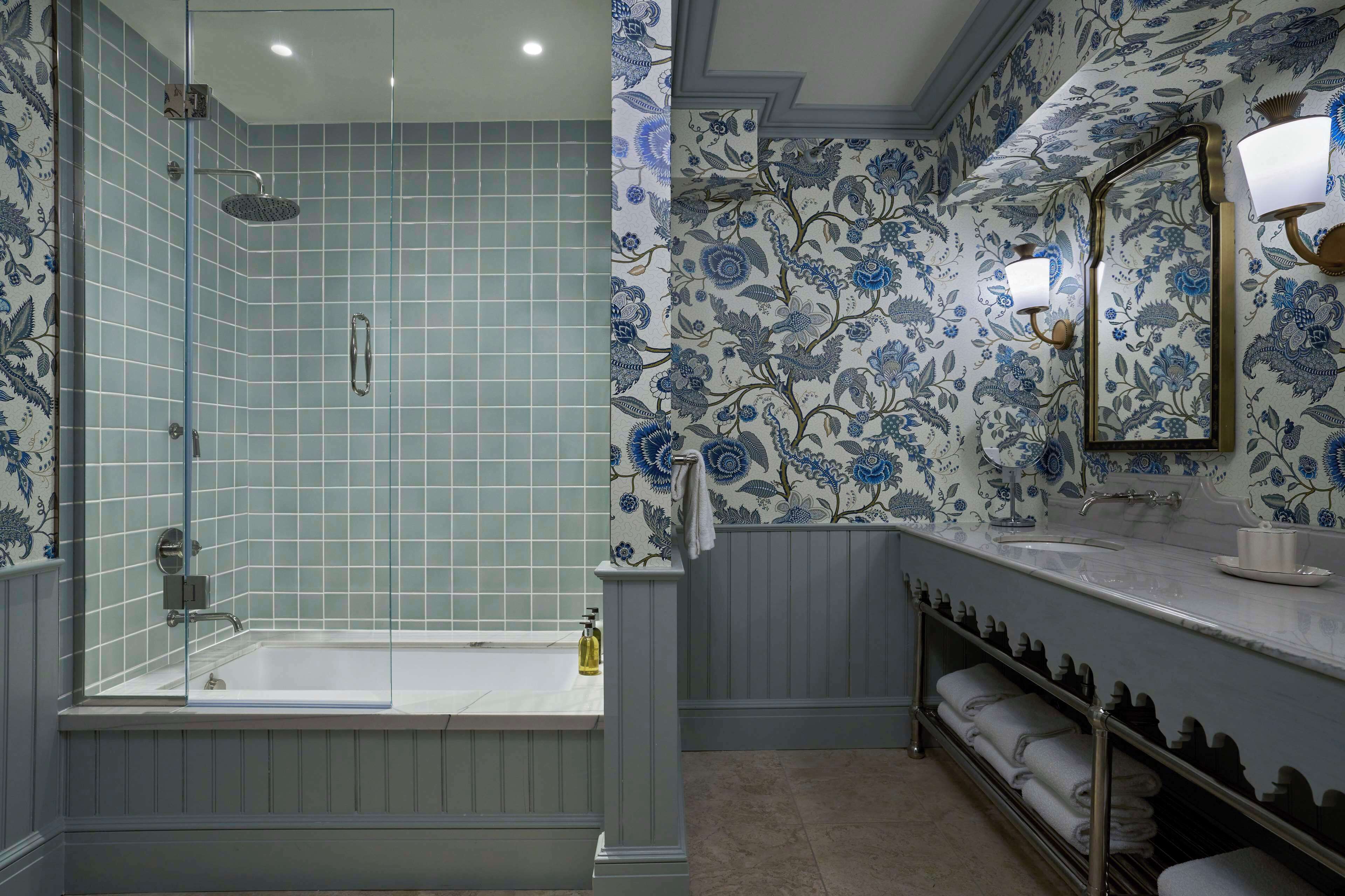 Une salle de bain avec une douche à parois de verre, une baignoire, un lavabo avec un miroir et un porte-serviettes.