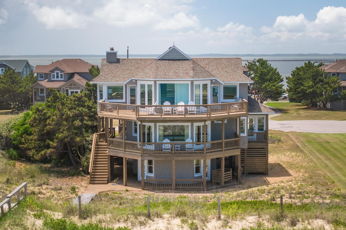 Une maison à deux étages avec un balcon, une terrasse et une vue sur l’eau.
