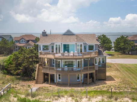 A two-story house with a balcony, a deck, and a view of the water.