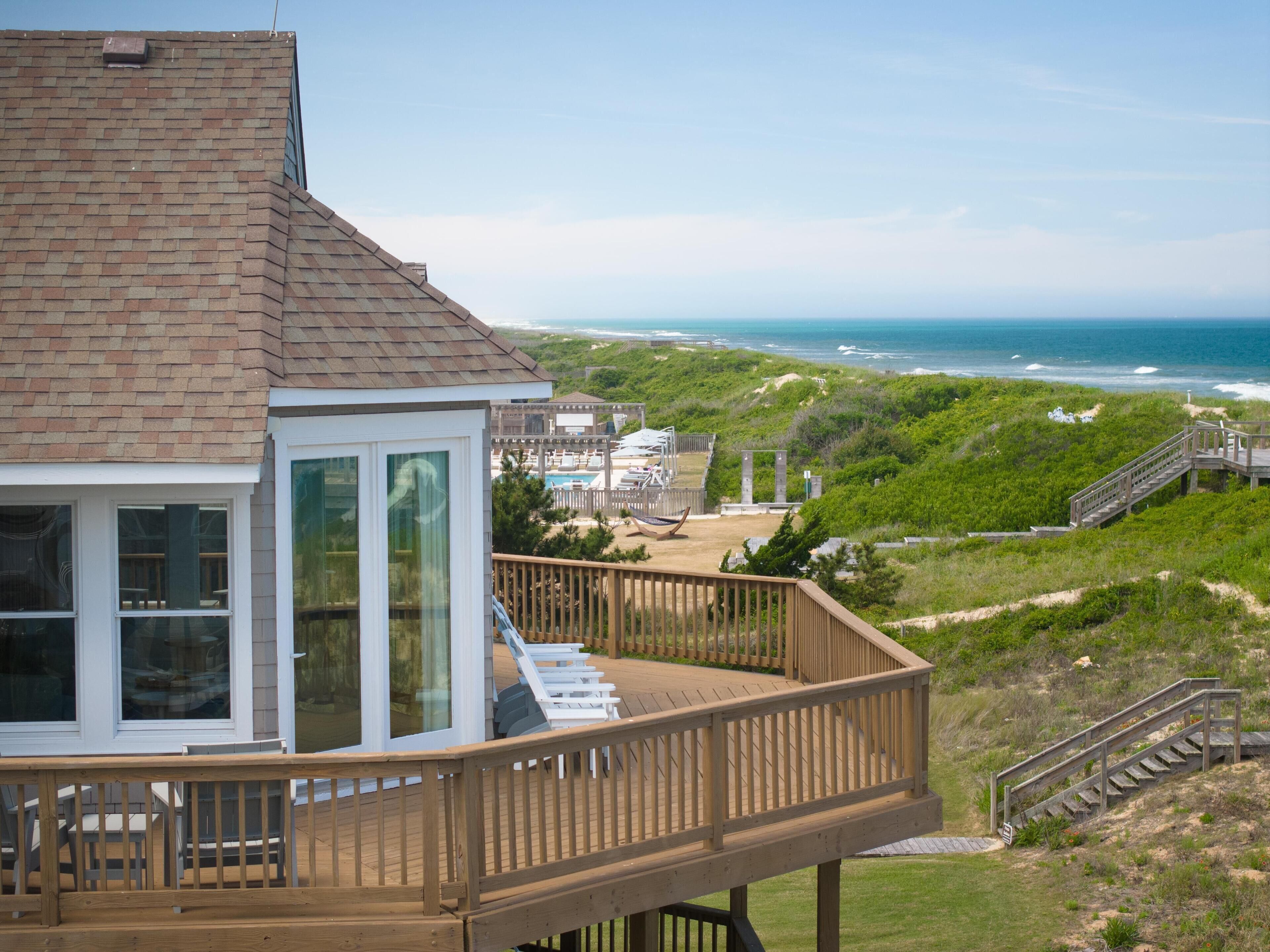 Ein Objekt direkt am Strand mit einer Holzterrasse, einem Wintergarten und Blick auf den Ozean.