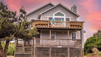 A two-story house with a wooden deck and a covered porch.