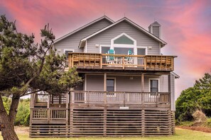 A two-story house with a wooden deck and a covered porch.
