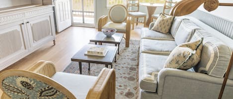 A spacious living room with a sofa, chairs, a coffee table, and a television.