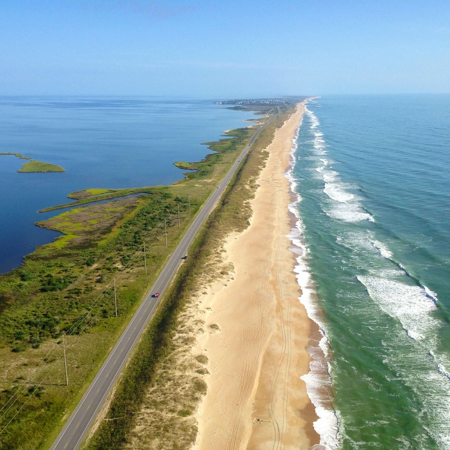 A coastal road with a beach on one side and a body of water on the other.