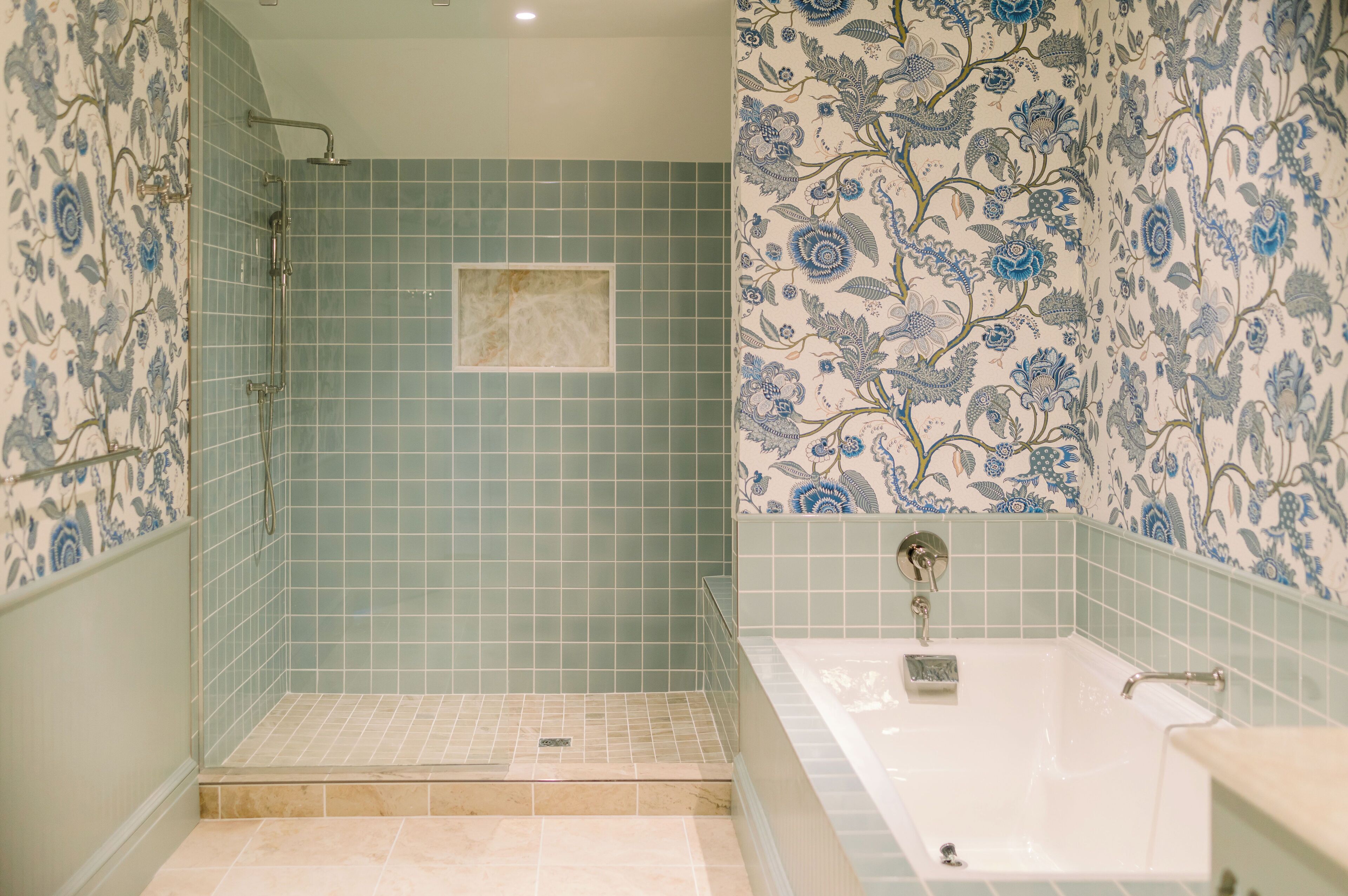 A bathroom with a shower, a bathtub, and floral patterned walls.