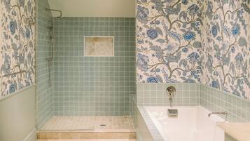 A bathroom with a shower, a bathtub, and floral patterned walls.
