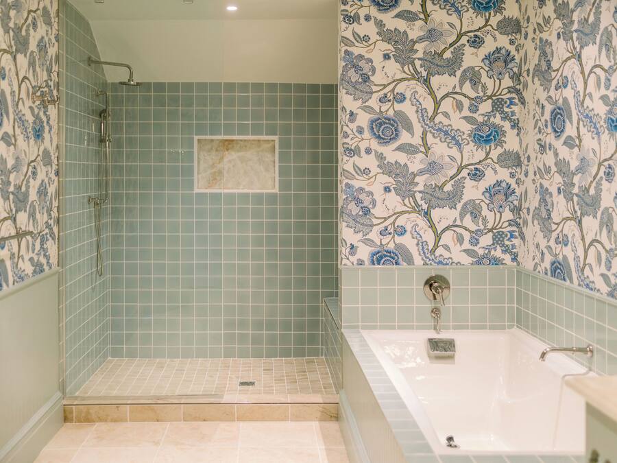 A bathroom with a shower, a bathtub, and floral patterned walls.