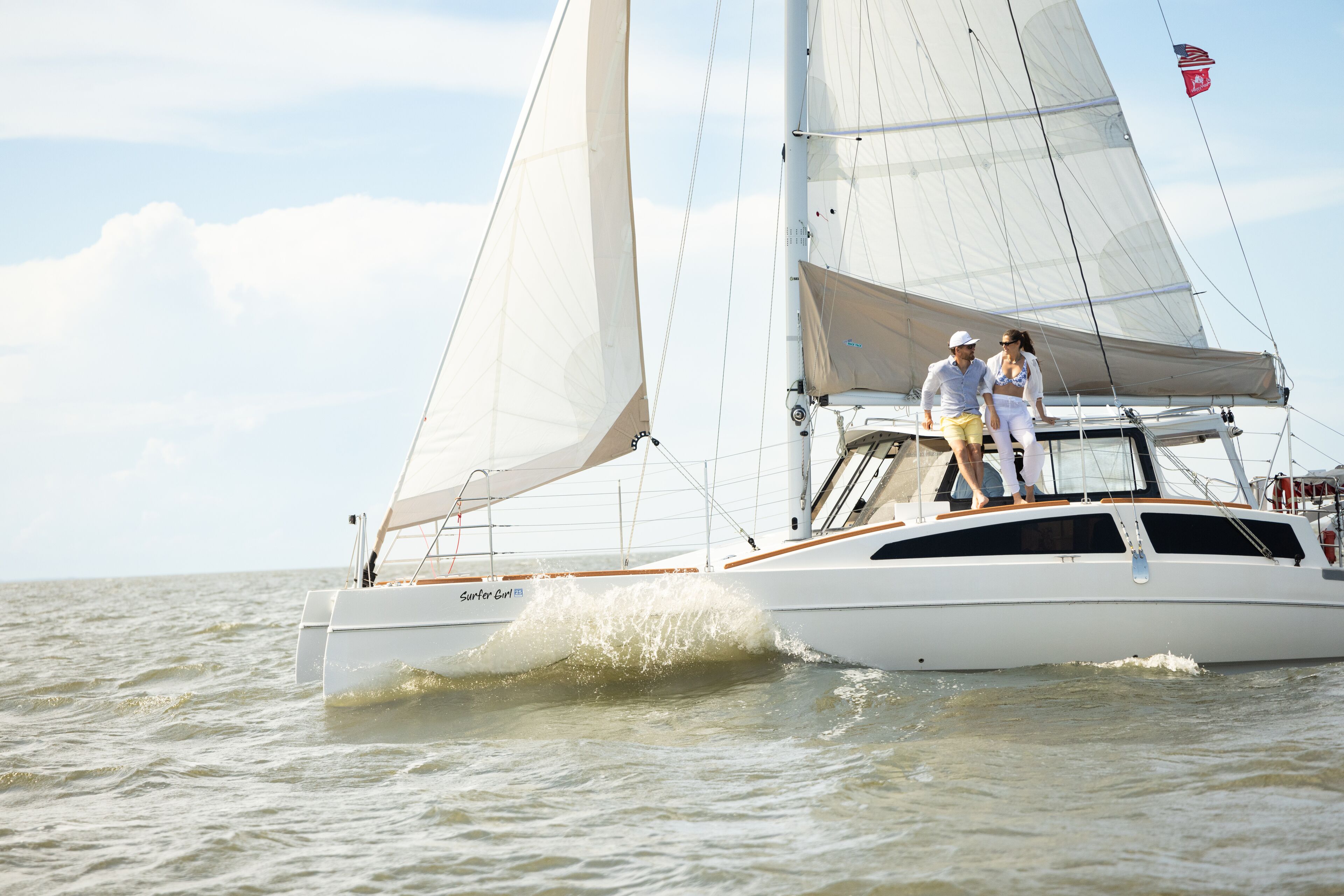 A sailboat with a cabin and a deck area where two people are standing.