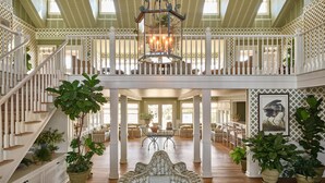 A spacious interior with a central seating area, a staircase, and a chandelier. - The Sanderling (Duck)