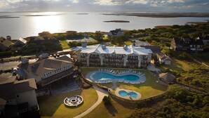 A large resort with multiple buildings, a central swimming pool, and a view of the ocean. - The Sanderling (Duck)