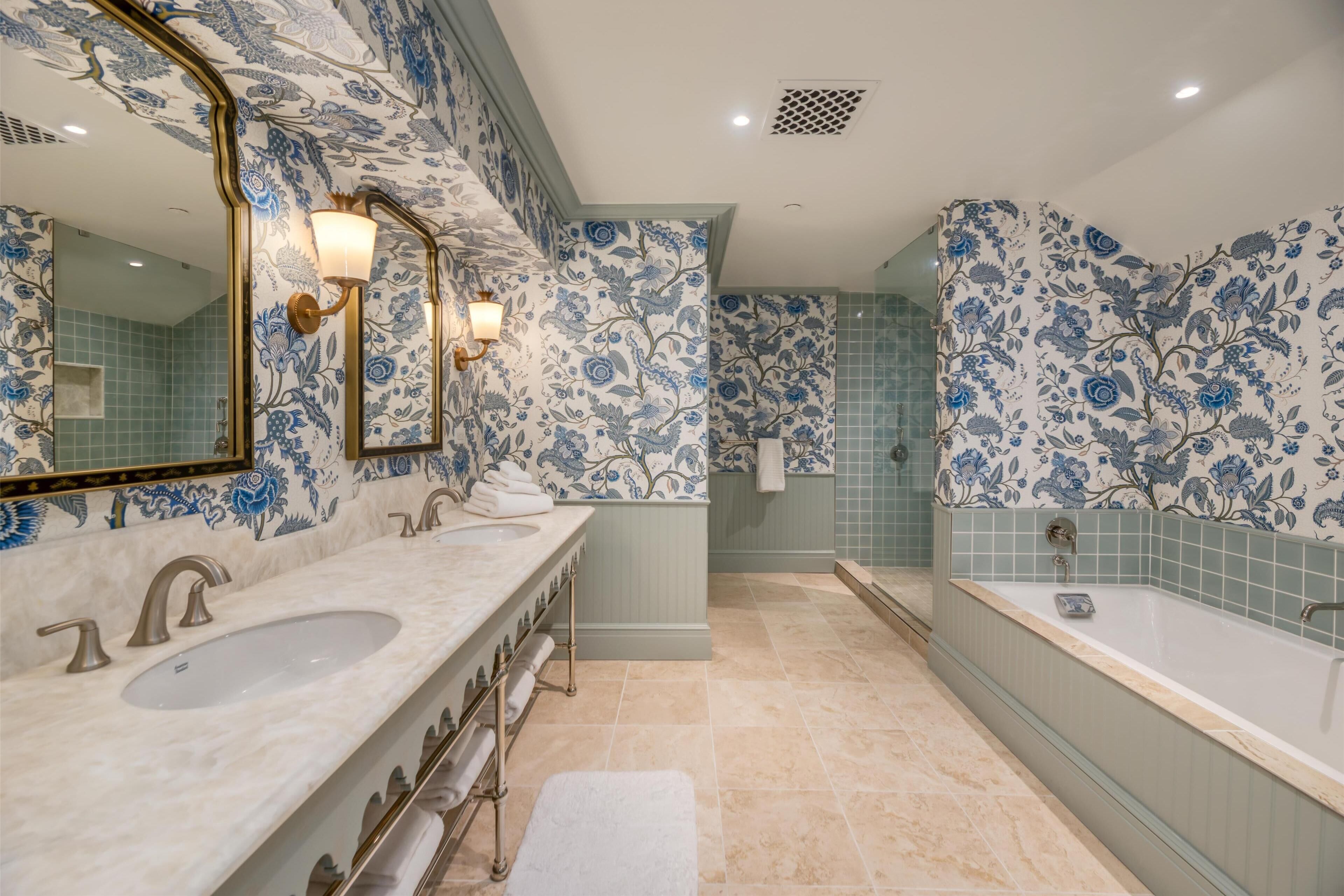 Une salle de bain avec deux lavabos, une grande baignoire et des murs décorés de motifs floraux.