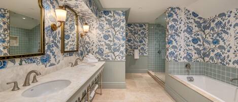 A bathroom with two sinks, a large bathtub, and floral patterned walls.