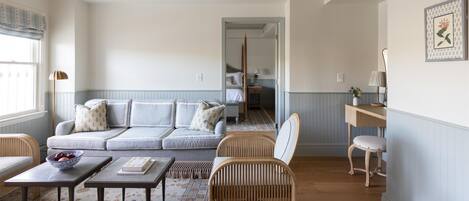 Una sala de estar con un sofá, dos mesas, una silla y una mesita con un cuenco.