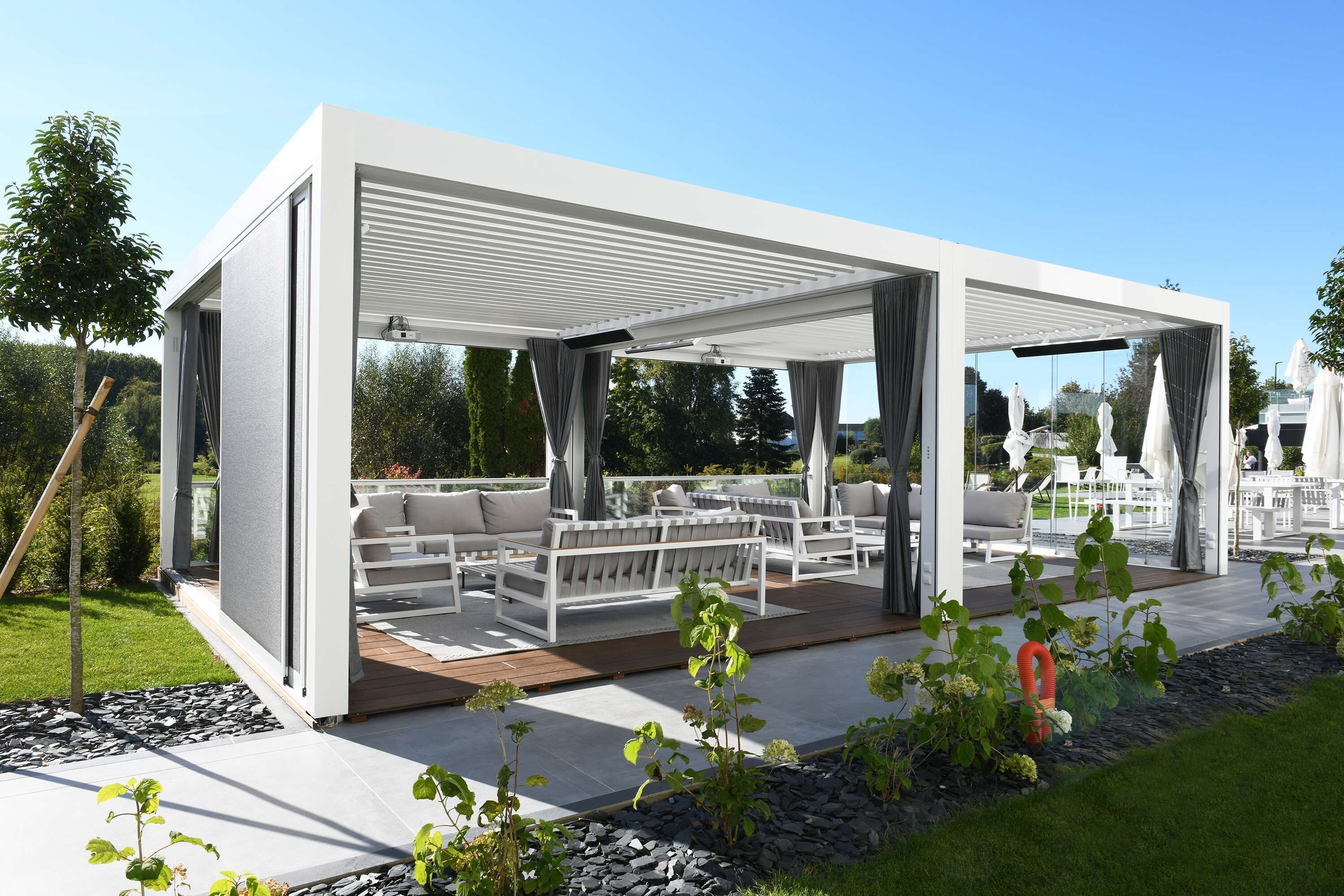 A modern outdoor lounge area with white furniture and a covered patio.