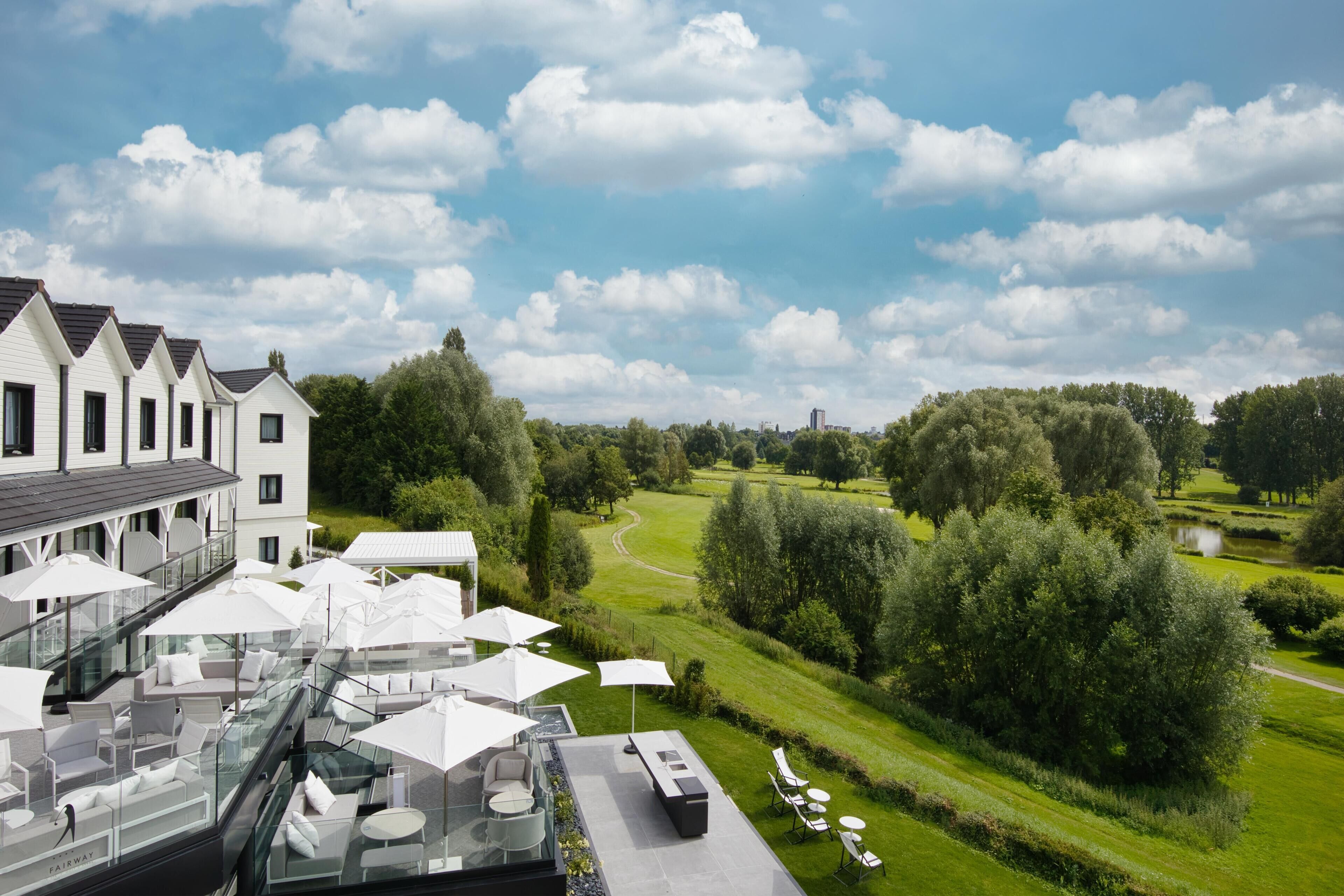 A rooftop terrace with outdoor seating and a view of a golf course.