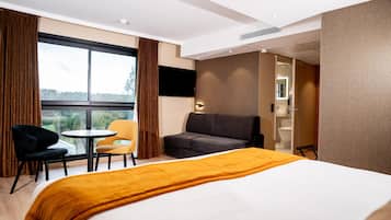 Et hotelværelse med seng, sofa, et lille bord og et fjernsyn.