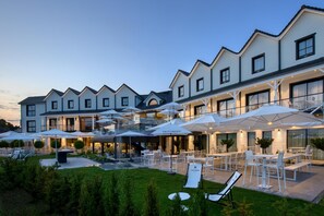 A hotel with outdoor seating, umbrellas, and a well-maintained garden. - Best Western Plus Le Fairway Hotel & Spa Golf d'Arras (Anzin-Saint-Aubin)