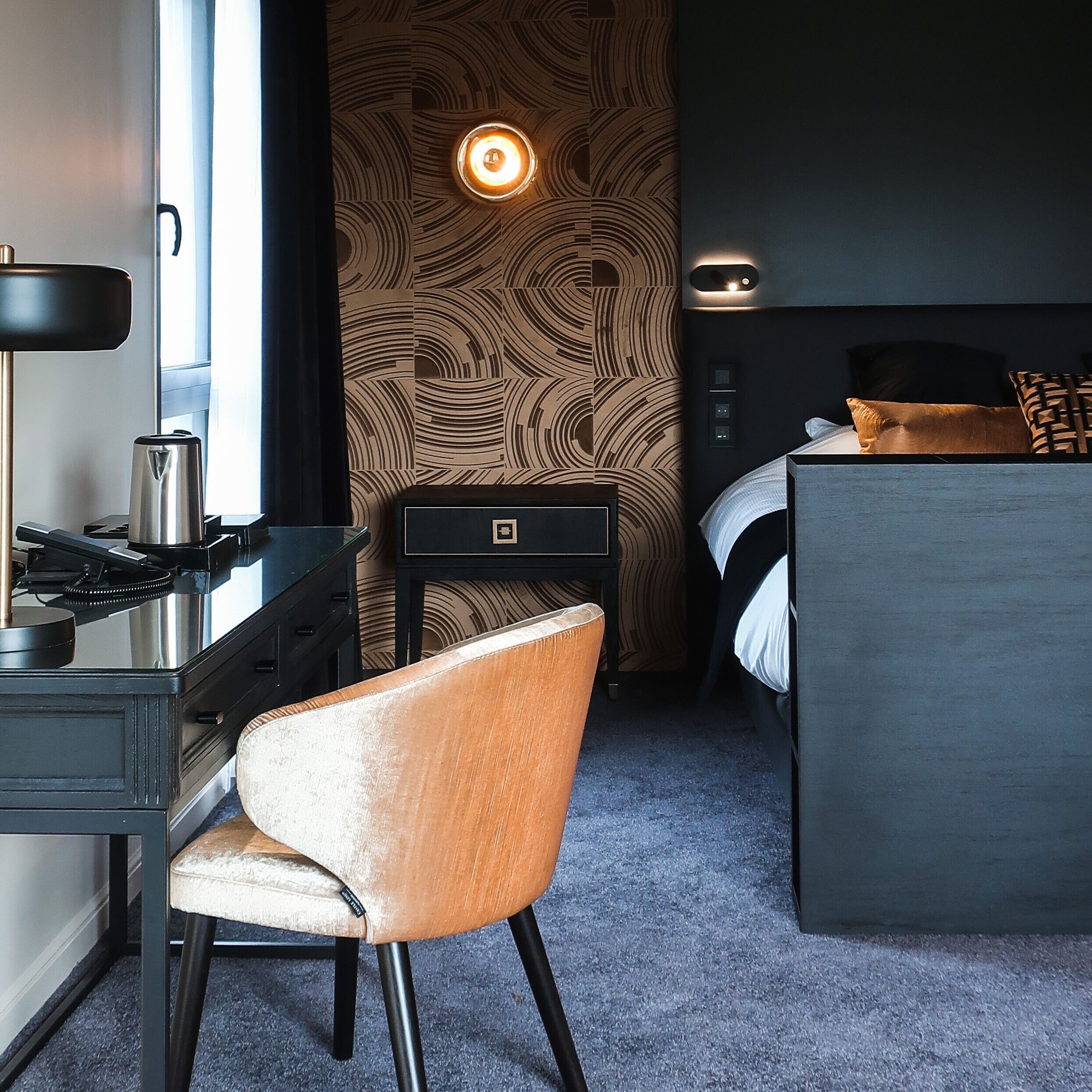 Une chambre d’hôtel moderne équipée d’un bureau, d’une chaise et d’un lit.