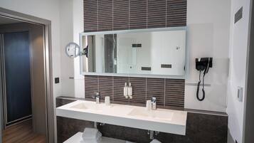 Un baño moderno con un espejo grande, dos lavamanos, un perchero para toallas y un teléfono.