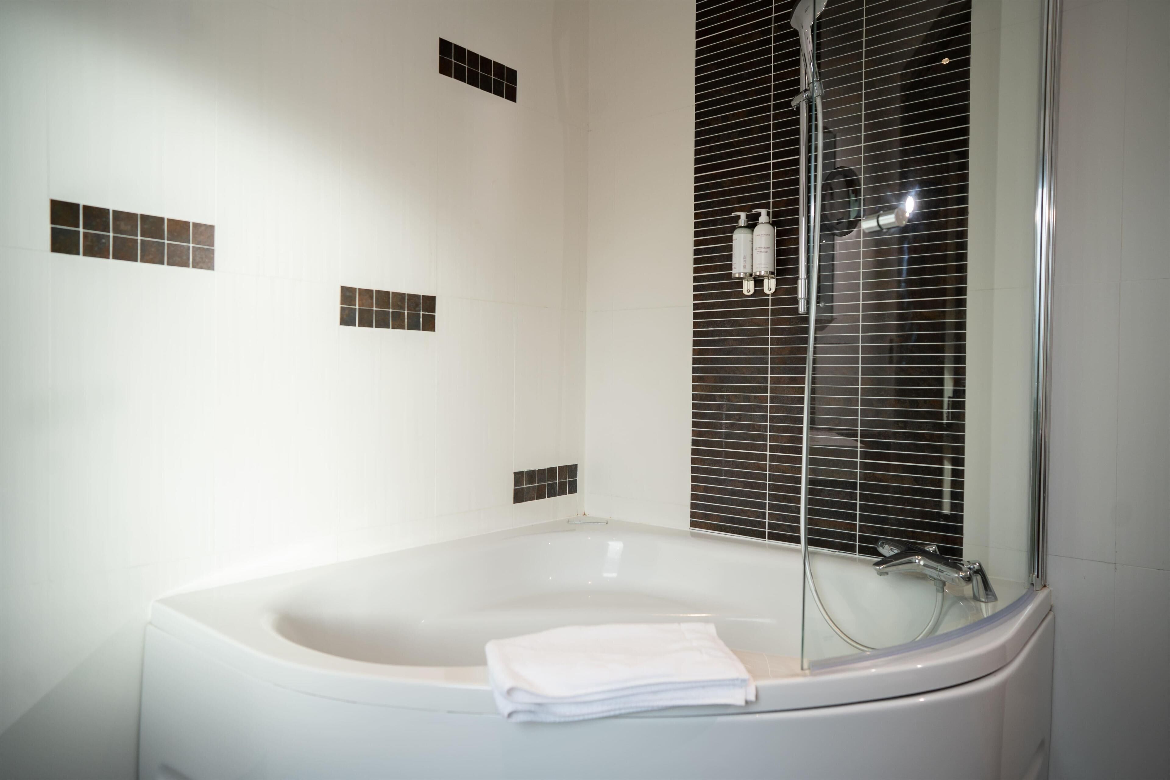 A modern bathroom with a freestanding bathtub, a shower enclosure, and a towel placed on the tub.