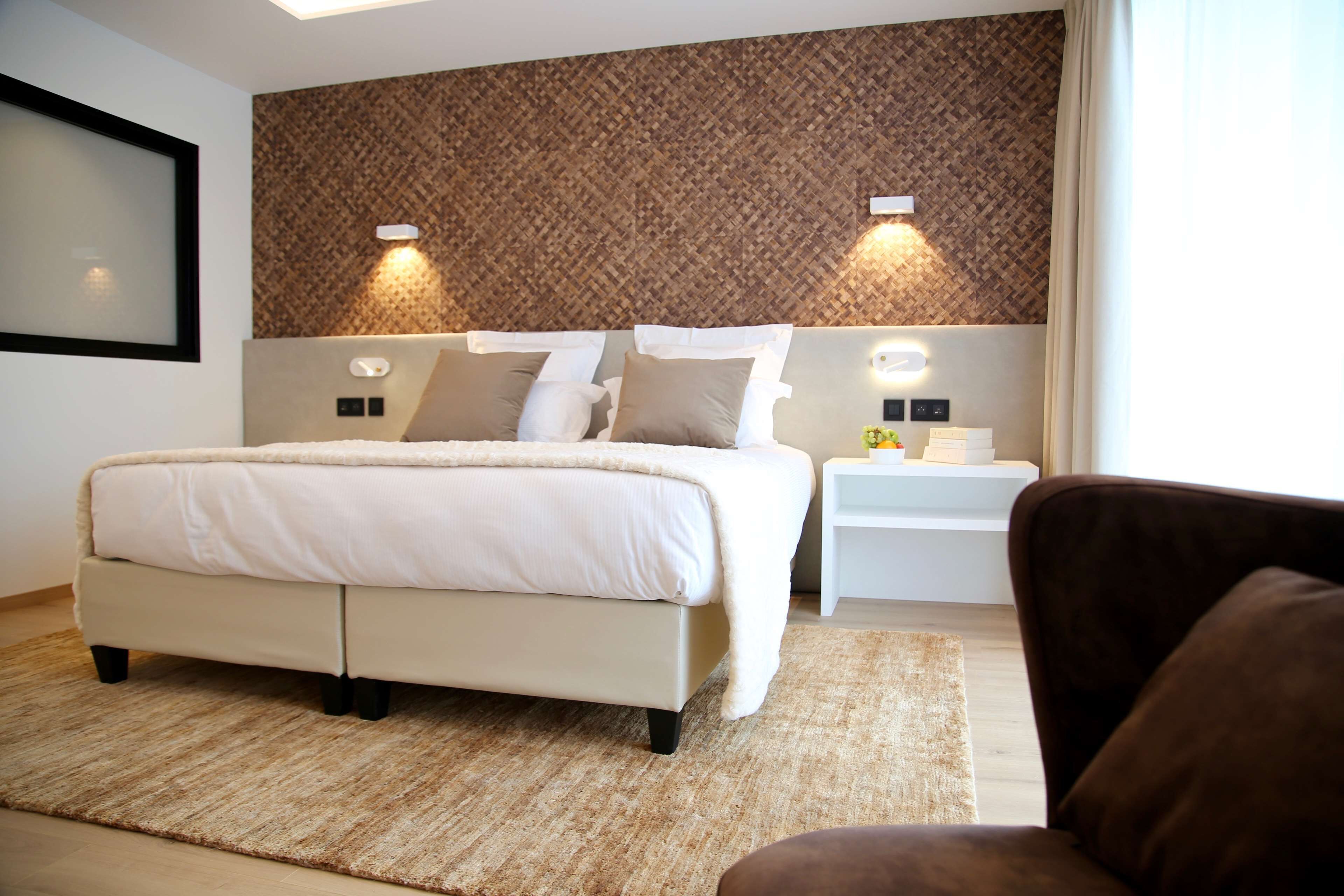 A modern bedroom with a large bed, two bedside tables, and a headboard with a woven pattern.