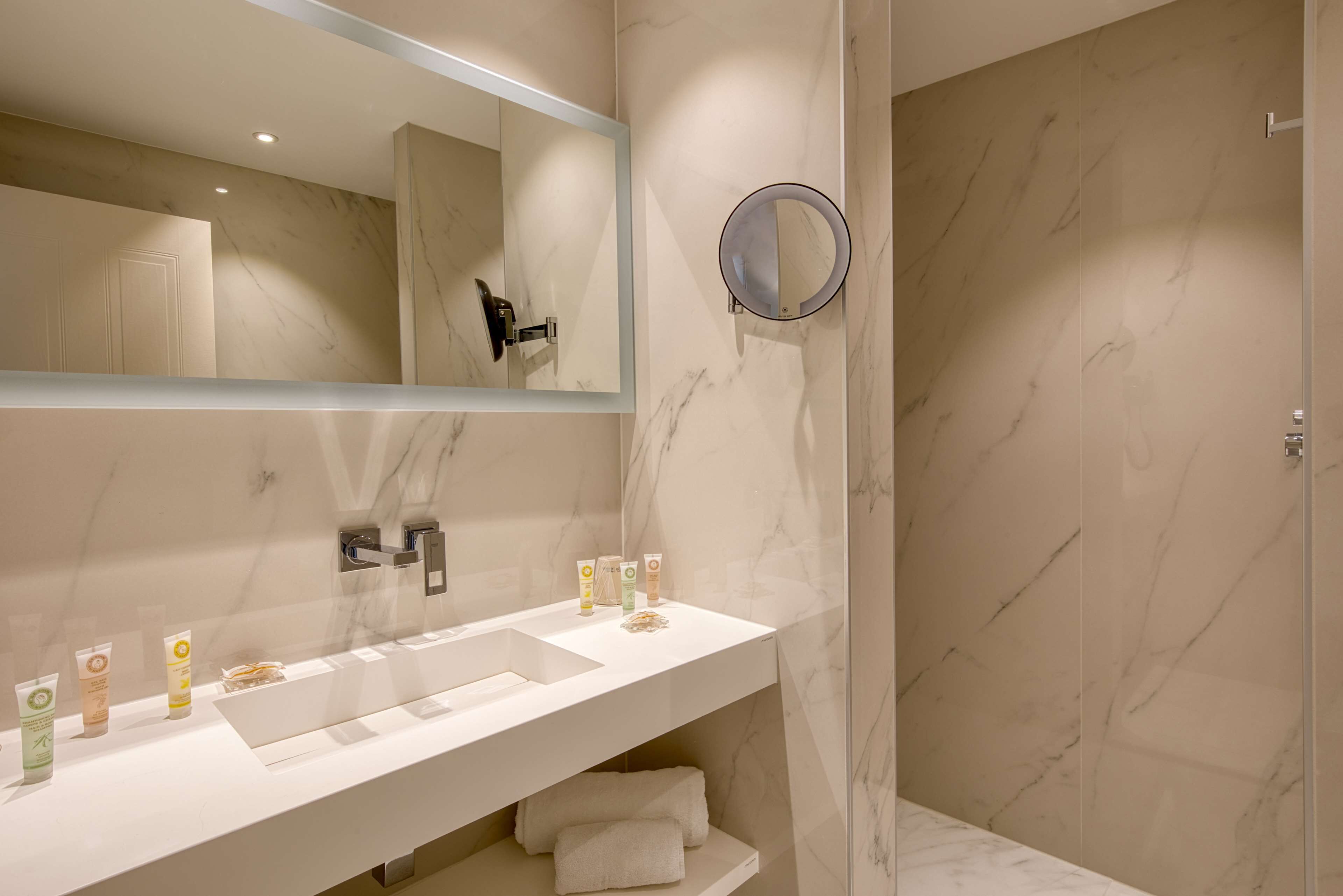 A modern bathroom with a large mirror, a sink, and a shower area.