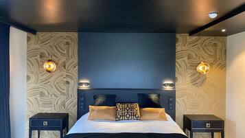 Une chambre moderne avec un grand lit, deux tables de chevet et des lampes fixées au mur.